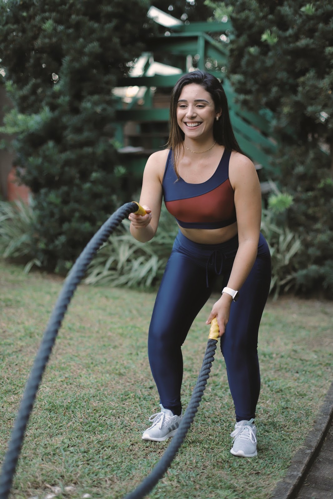 Carol Magatão sorrindo durante um treino ao ar livre com corda ondulatória
